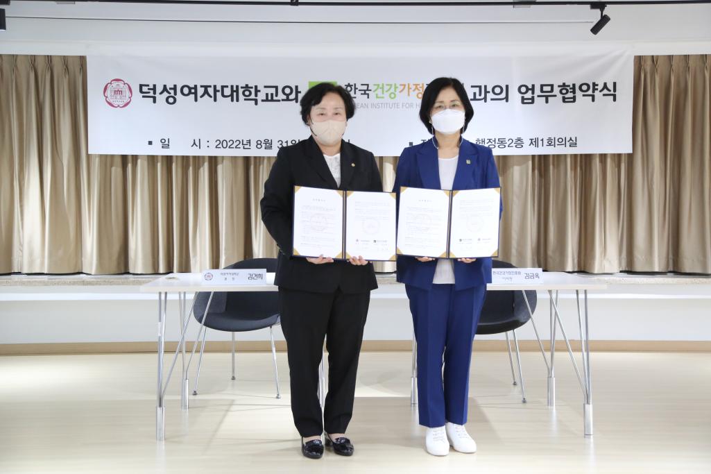 덕성여자대학교와 한국건강가정진흥원과의 업무협약식 플랜카드 앞에서 상장을 들고 포즈를 취하는 대표들